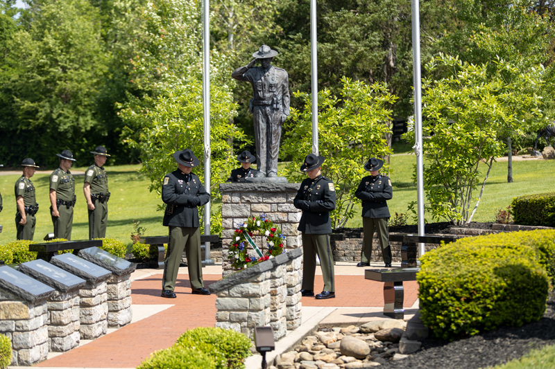 Four conservation officers in color guard stand in prayer around the memorial statue