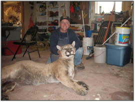 man smiling and holding up a head of a mountain lion