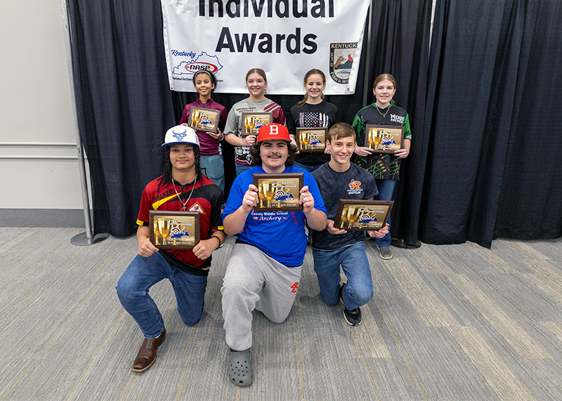 Seven Students holding up placards in front of a sign that reads individual awards
