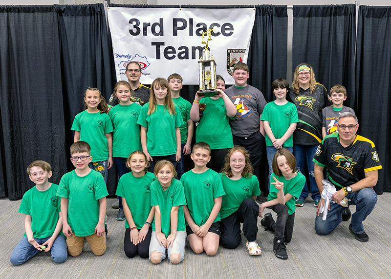 A group of eighteen students in front of a sign that reads 3rd place team