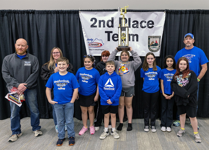 A group of eight students and three adults in front of a sign that reads 2nd place team