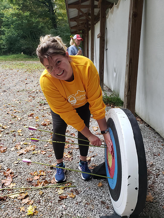 A woman pulling arrows out of a target