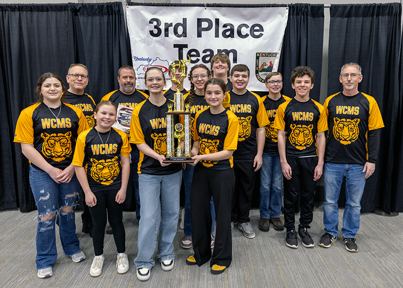 A group of nine students and two adults in front of a sign that reads 3rd place team