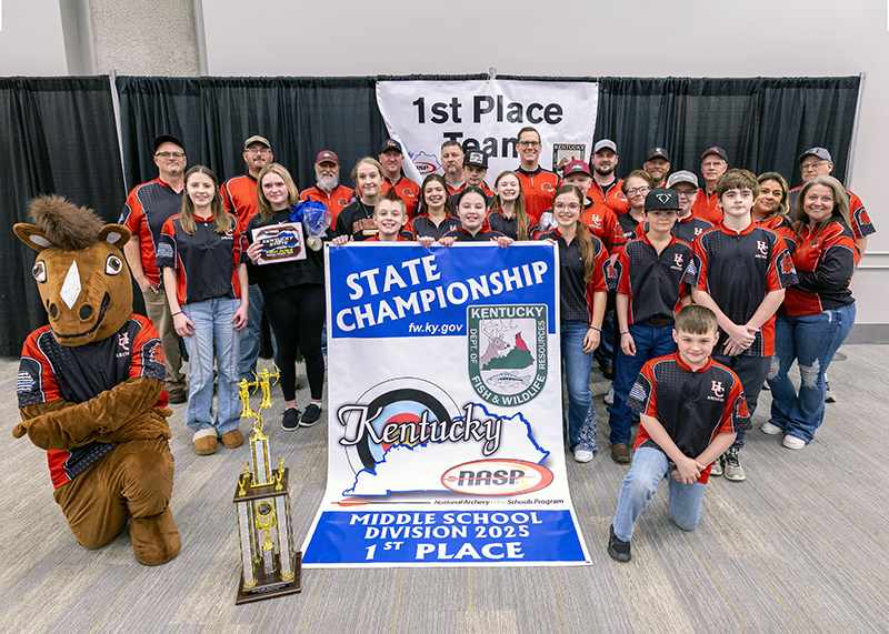 A group of twelve students and eleven adults in front of a sign that reads 1st place team. They are standing with a horse. They are holding a banner that reads middle school division 1st place