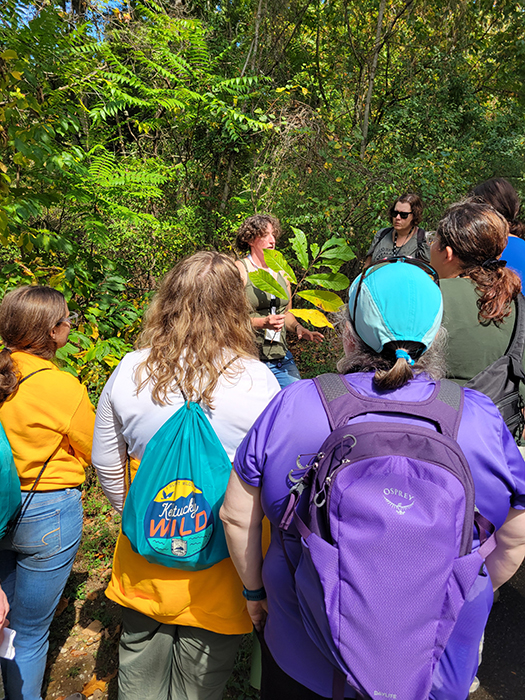 An instructor teaching a group while holding up a plant