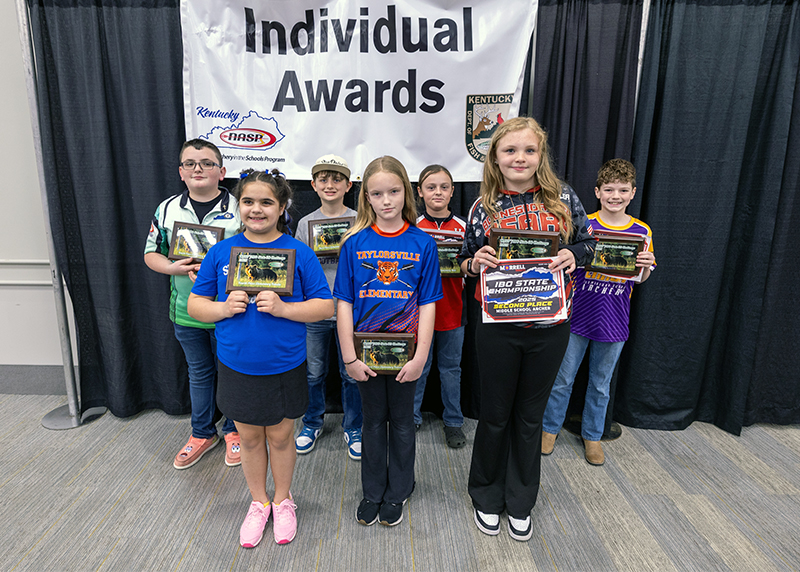 A group of seven students holding up a placards in front of a sign that reads individual awards
