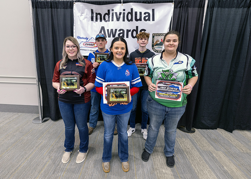 A group of five students holding up a placards in front of a sign that reads individual awards