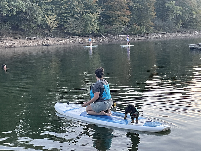 A woman floating on a kayak with a small dog