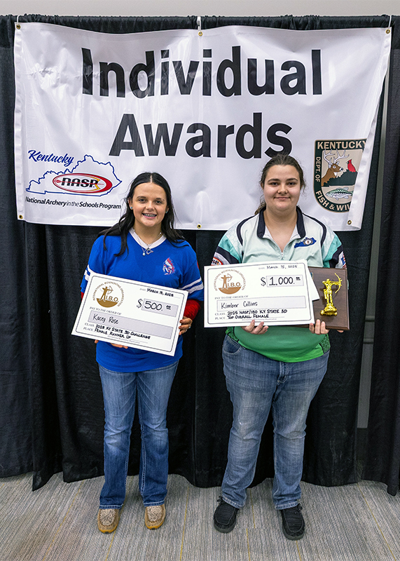 Two students standing in front a sign that reads individual awards and holding up certificates