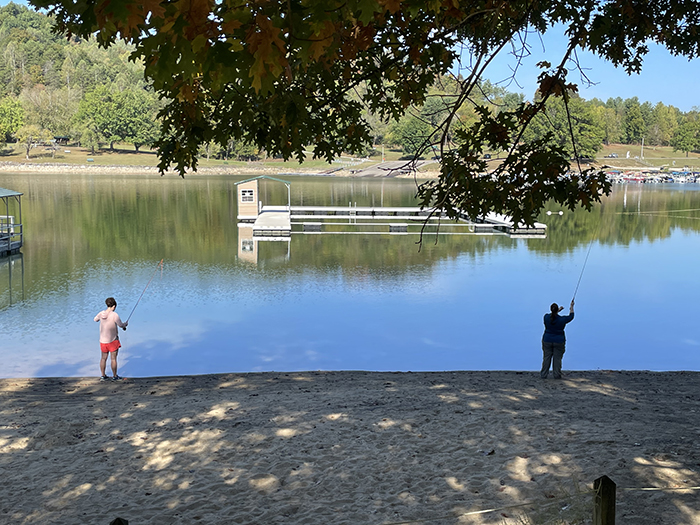 two people casting at the edge of a lake