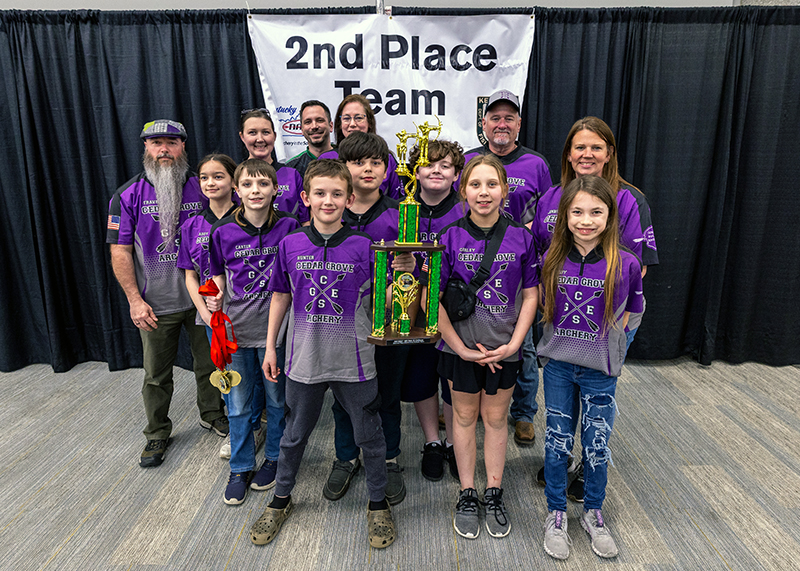 A group of seven students and six adults in front of a sign that reads 2nd place team