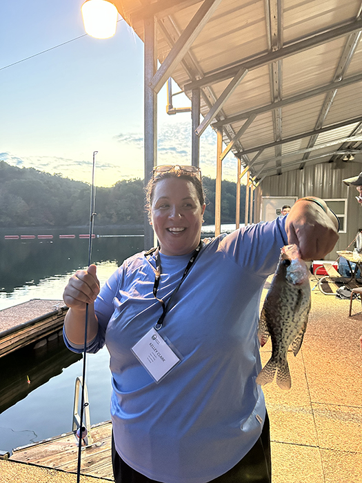 a woman holding up a recently caught sunfish