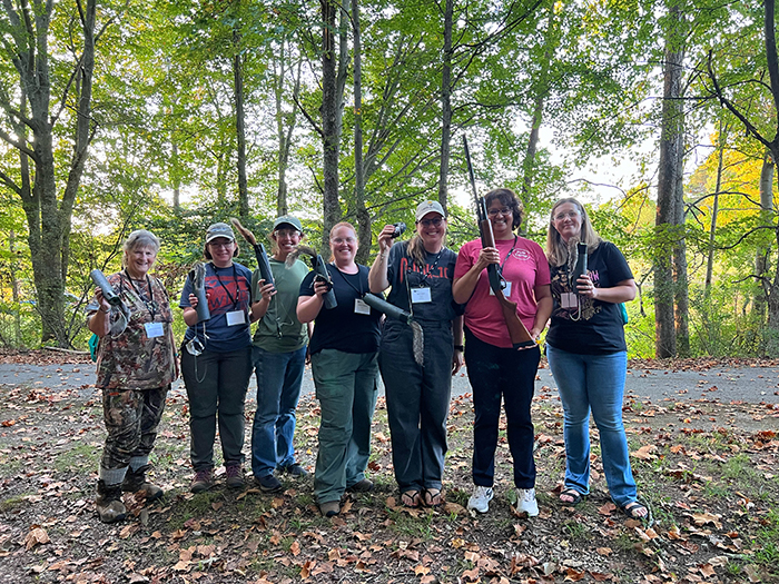 a group of seven women holding rifles and squirrel targets