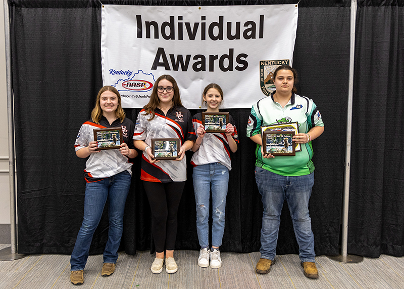 four students holding up award plaques in front of a sign that reads individual awards