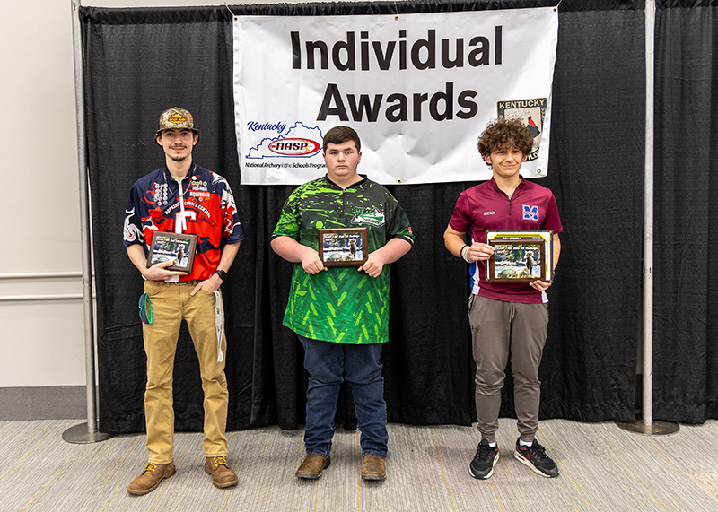 three students holding up award plaques in front of a sign that reads individual awards