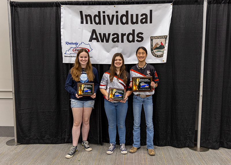 a group of students holding up plaques with a sign behind them reading individual awards