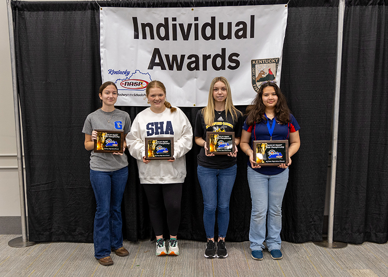 a group of students holding up plaques with a sign behind them reading individual awards