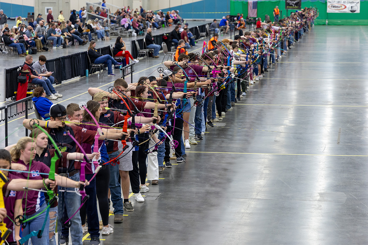 a large line up of students shooting archery in a lineup