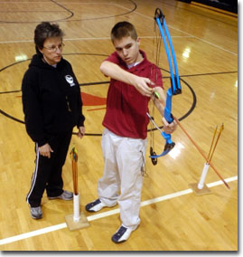 Student shooting with instructor in a gym