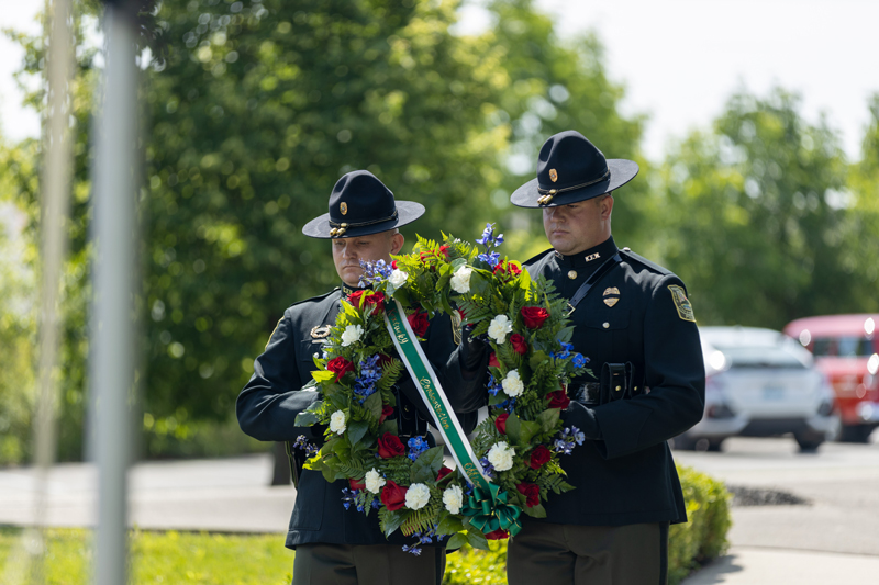 Two officers are carrying a floral wreath to the memorial