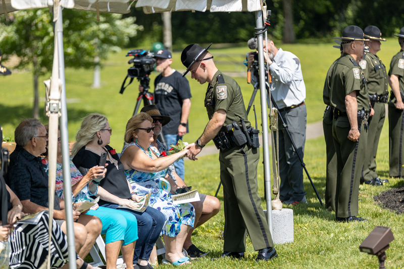 A Conservation Officer is giving flowers to people seated under a tent