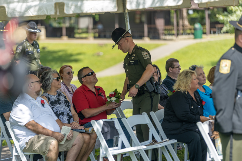 A Conservation Officer is giving flowers to people seated under a tent