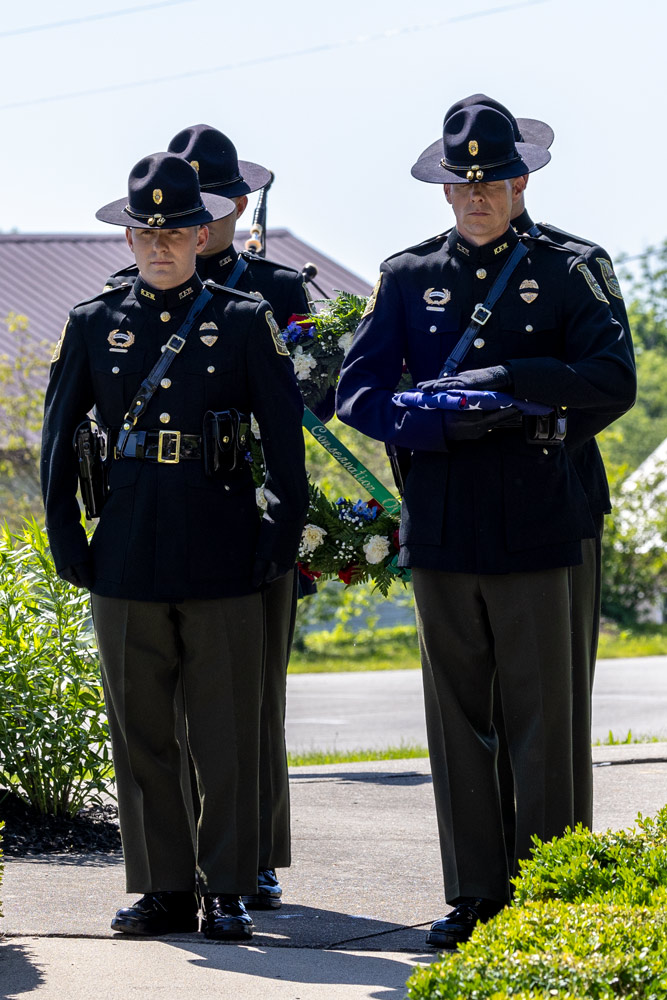 Four Officers are walking and carrying a folded flag and wreath