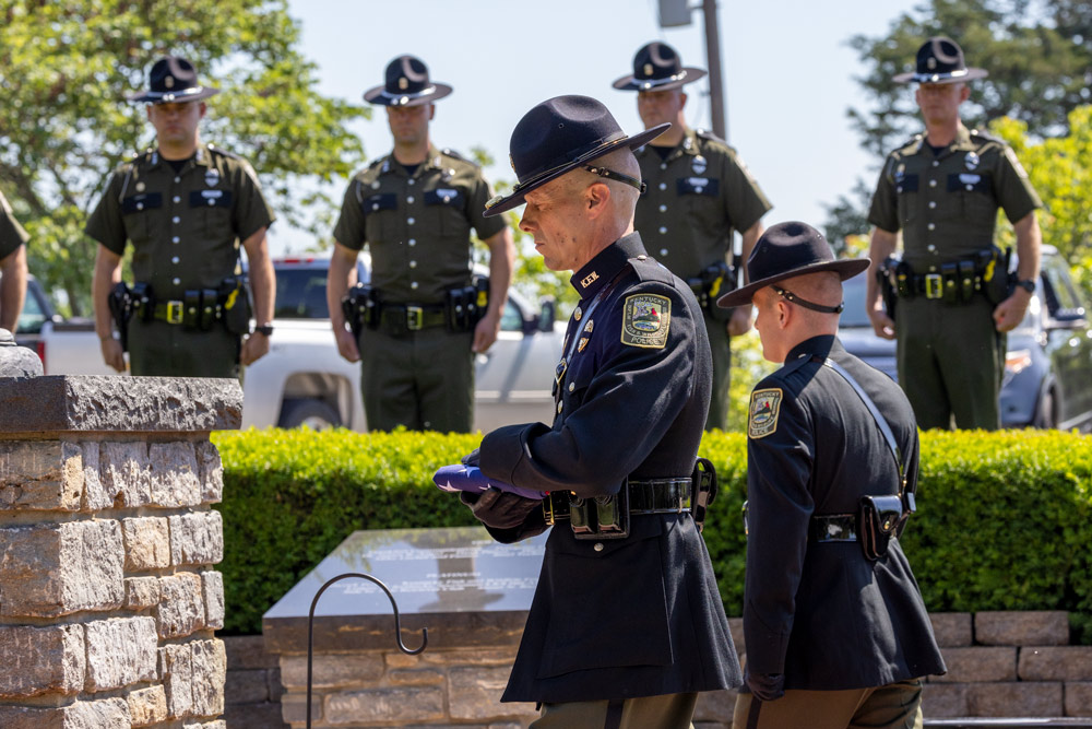 two officers are standing in the center of the memorial. Officers are lined up around it.