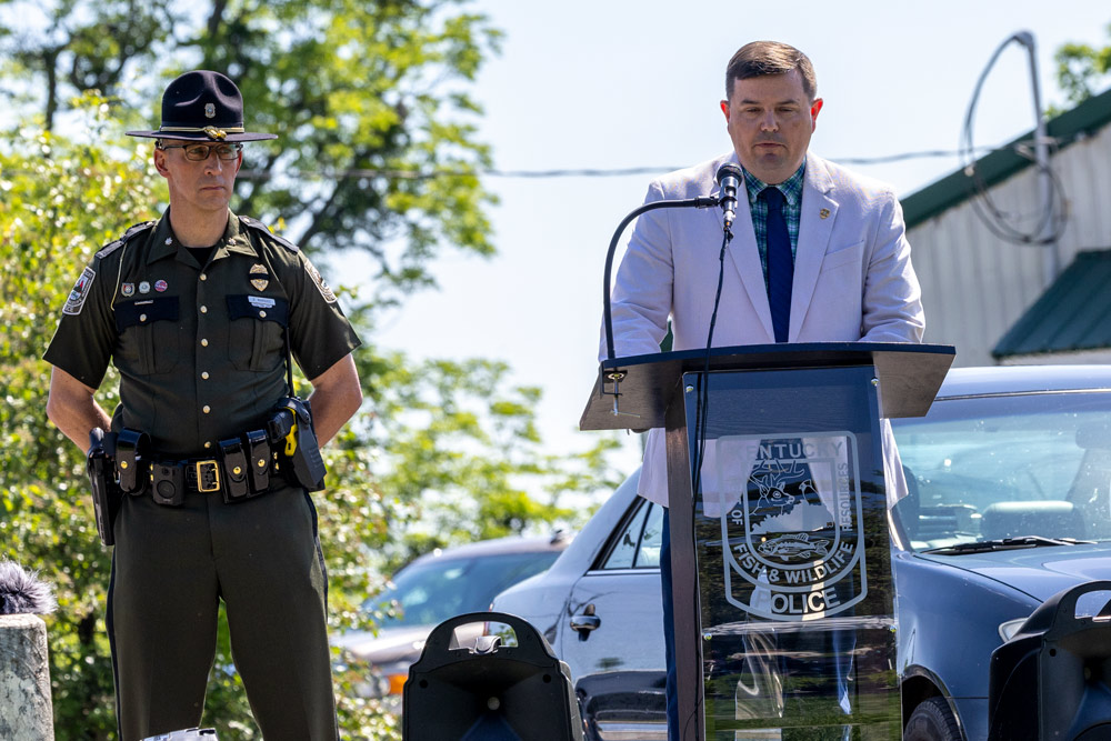 The Commissioner is speaking at a podium as a man stands to his right