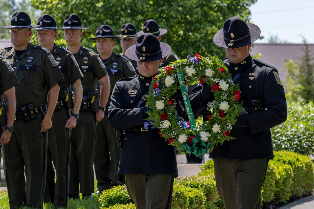 Two officers are carrying a wreath as a line of officers stands to the left