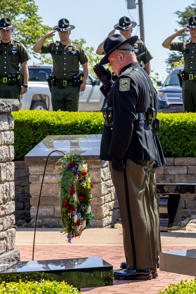 An officer is standing at attention to a wreath in the center of the memorial