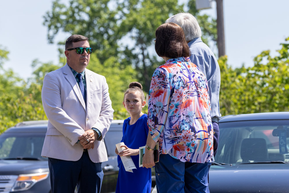 The commissioner is standing and speaking with a man a woman and a child