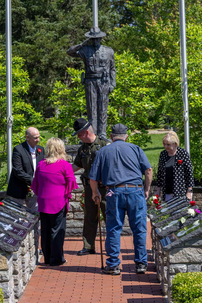 An officer is speaking with a group of two men and two women in the center of the fallen officer memorial