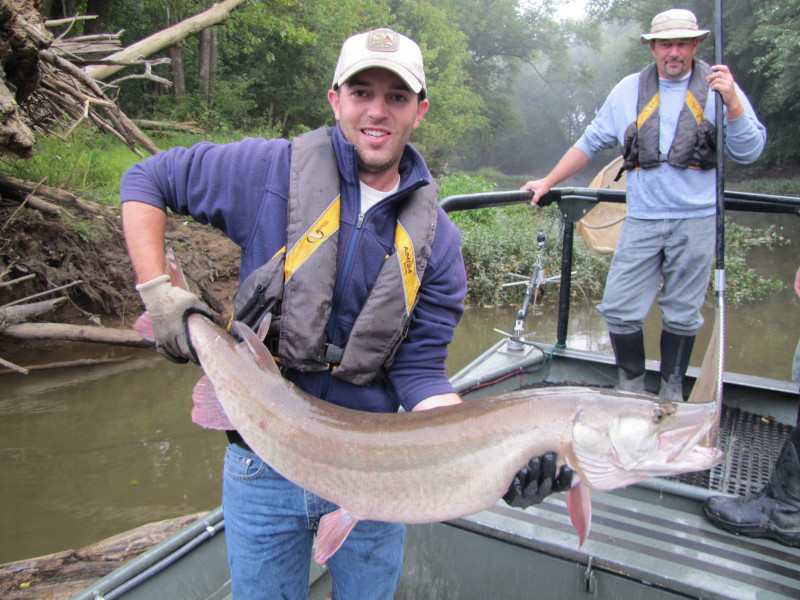 A young man is holing up a large muskellunge