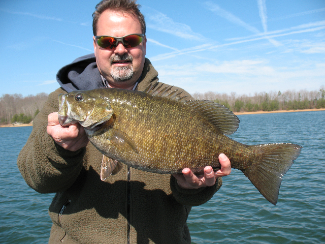 a man is holding up a large smallmouth bass