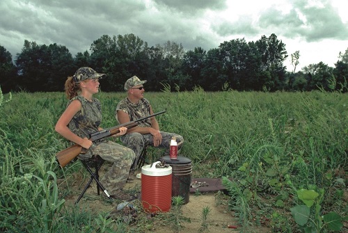 two hunters seated in a grassy field