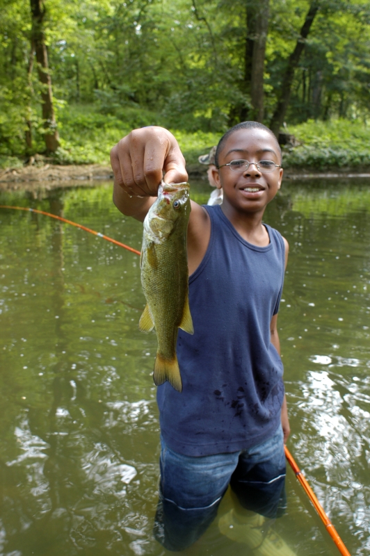 A young boy is holding up a smallmouth bass he caught for the camera