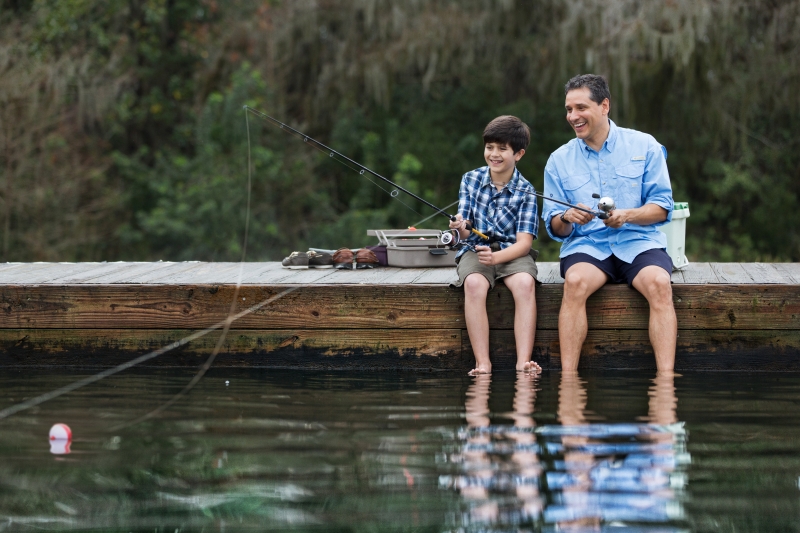 a man and a boy are seated on a dock fishing