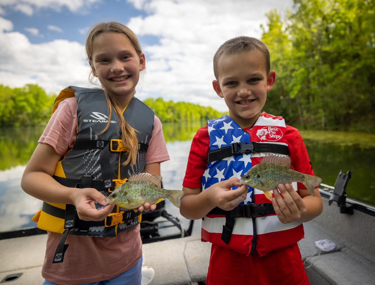 Two kids holding up recently caught sunfish