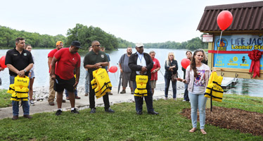 Woman speaking in a group in front of a Life Jacket Loaner Station