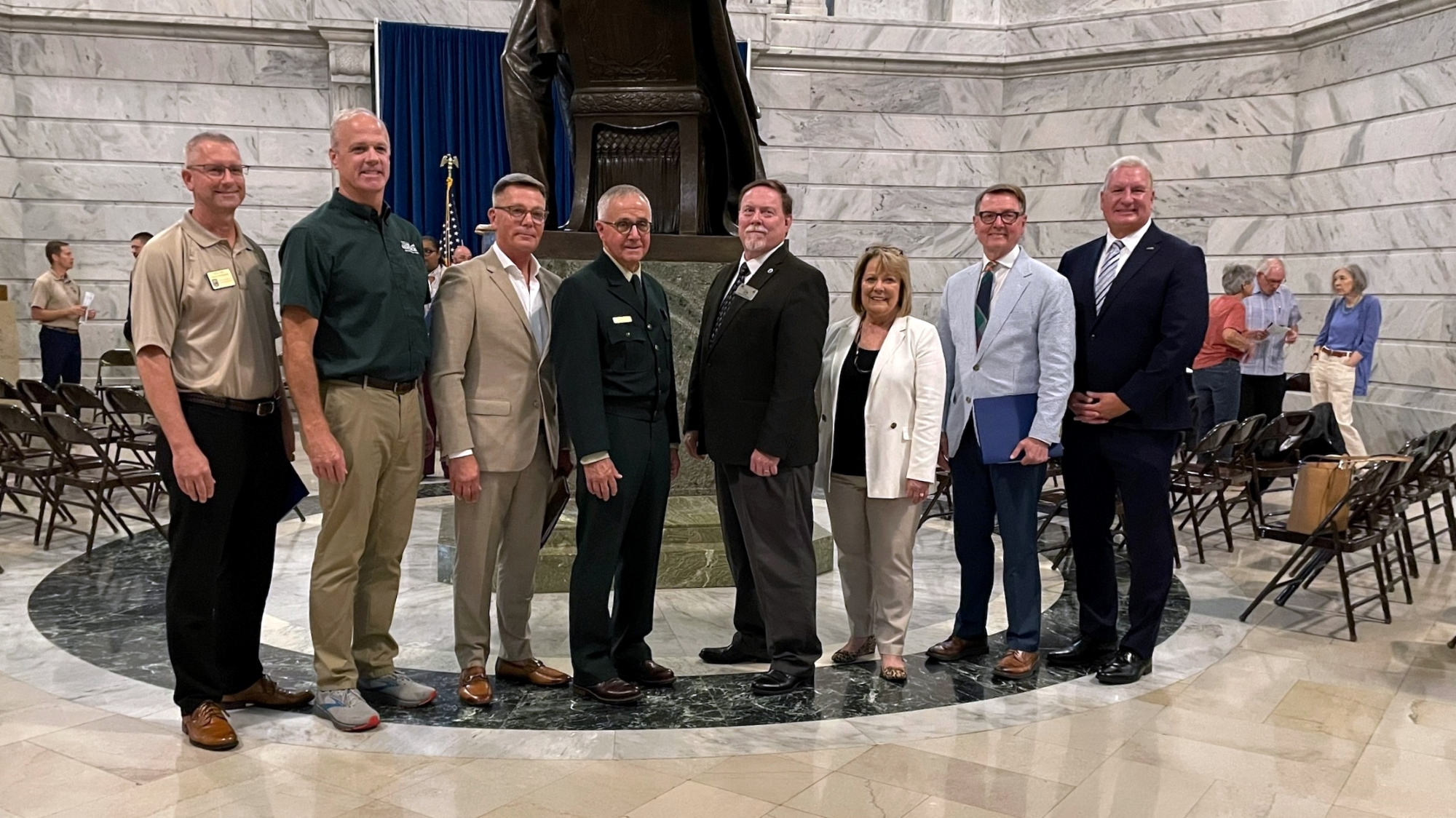 Group photograph showing eight people standing for the camera. Standing on the far left is Deputy Commission Brian Clark.