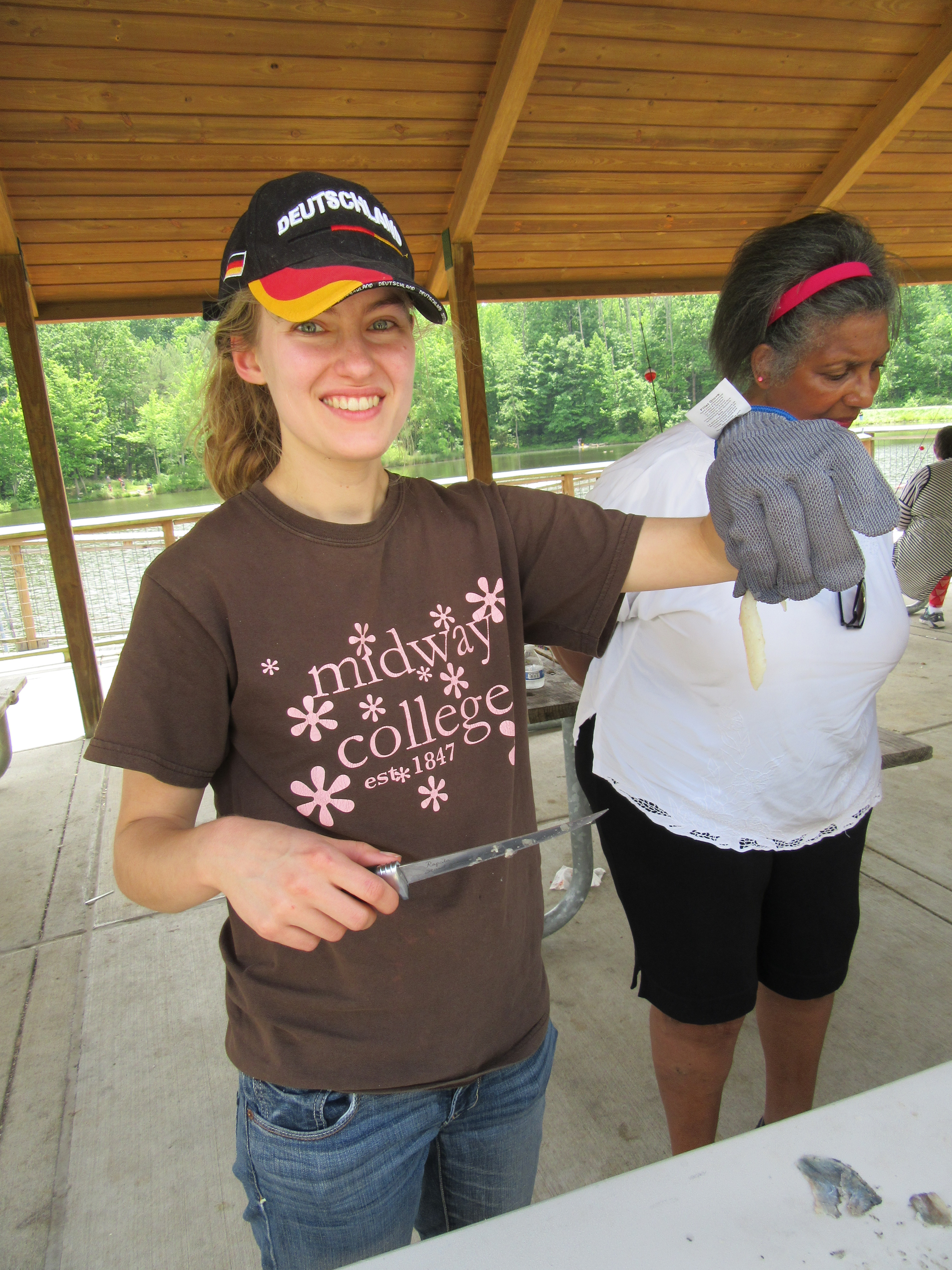 Image showing a Girl smiling for the camera as she displays a knife in her left hand and cut fish in her right