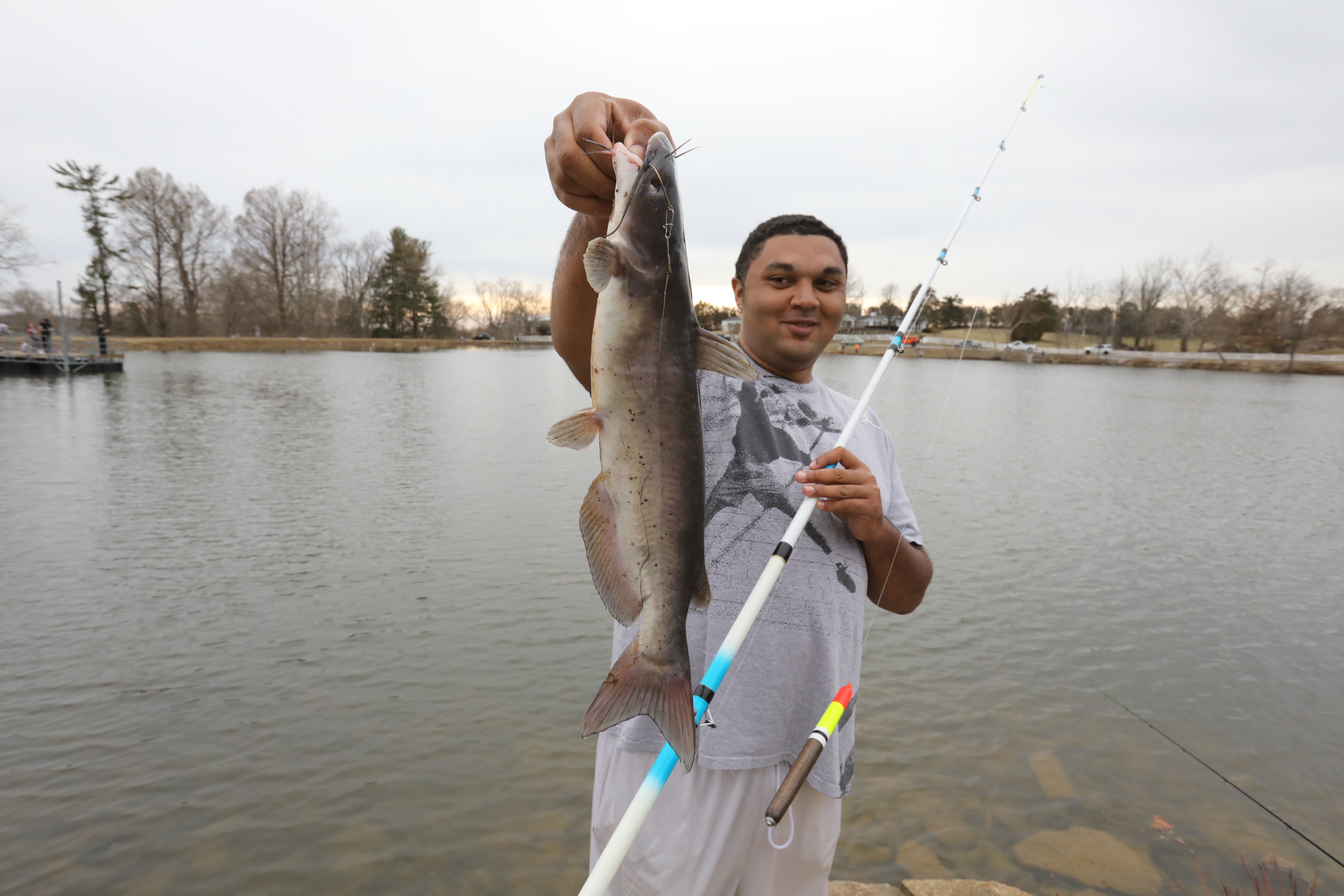 A young man is holding up a freshly caught catfish from the Upper Sportsmans Lake in Frankfort Kentucky, Spring 2022