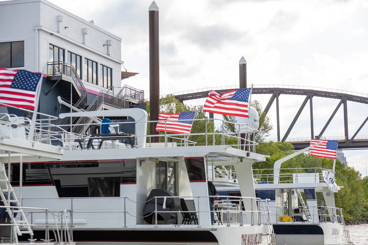 American flags are waving on the dock of a parked riverboat